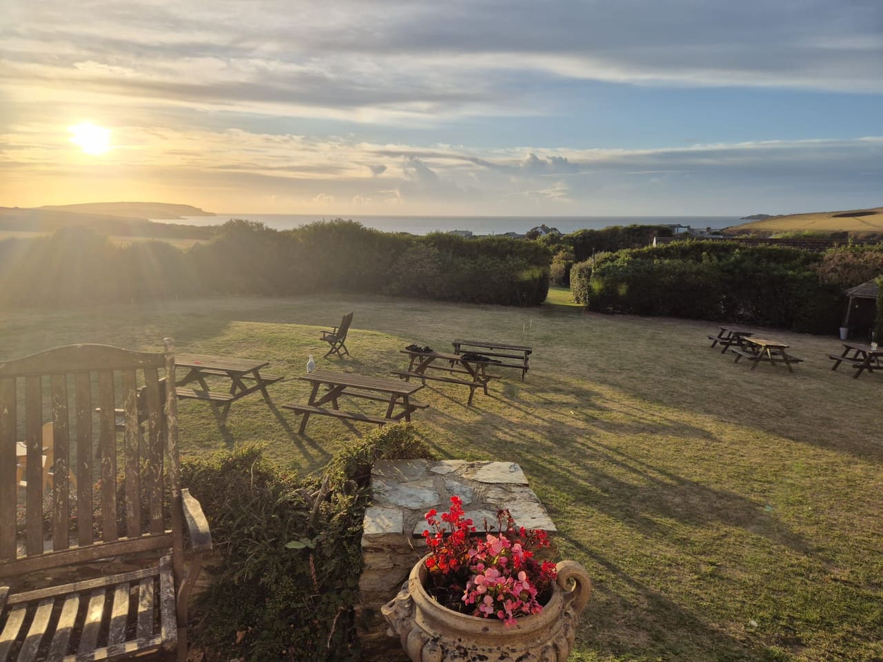 Picnic benches on the lawn as the sun sets over the coast