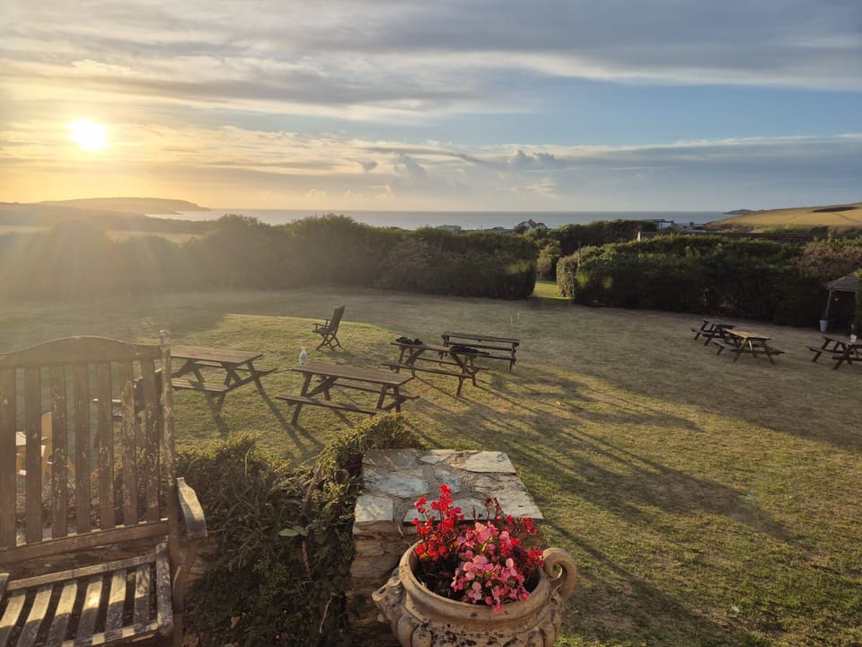 Picnic benches on the lawn as the sun sets over the coast